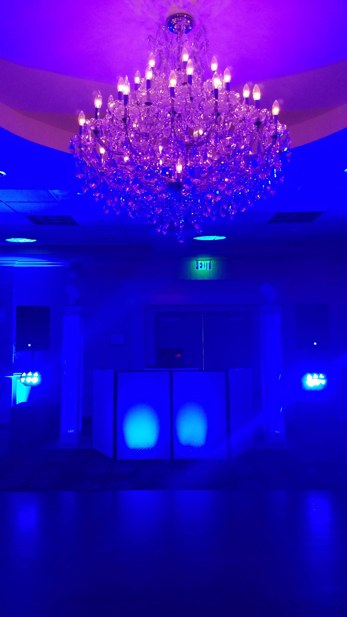 The white DJ setup glowing in a chandelier ballroom