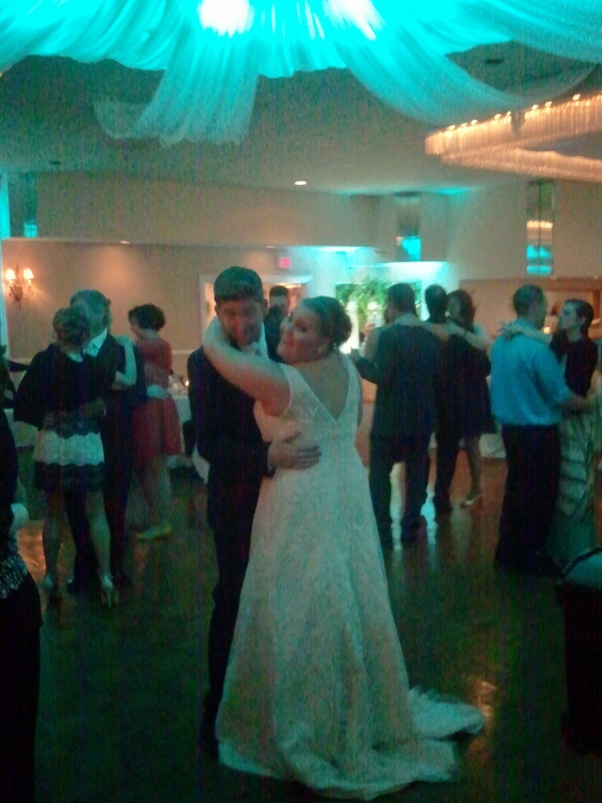 A couple’s first dance under elegant teal wedding lighting