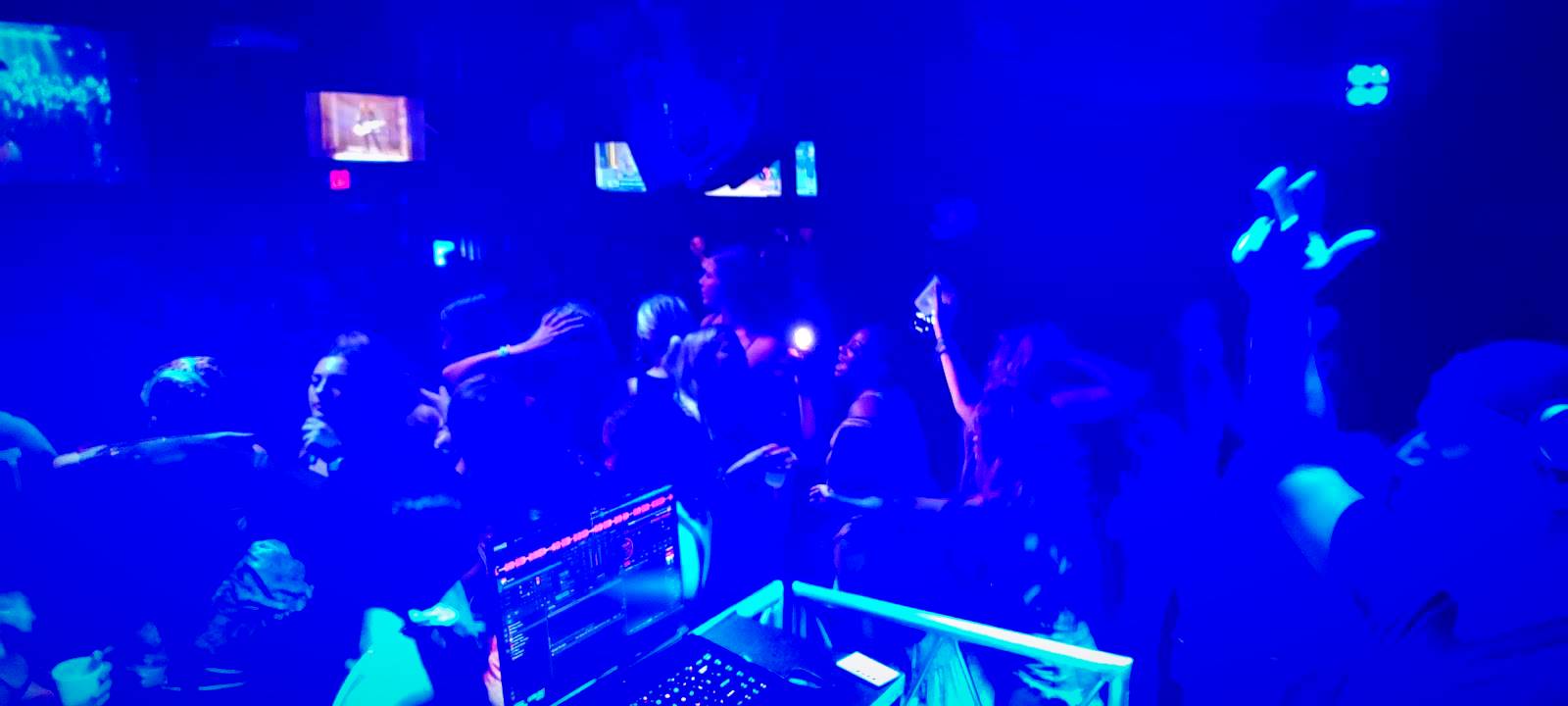 Packed nightclub floor under blue lighting from the DJ booth